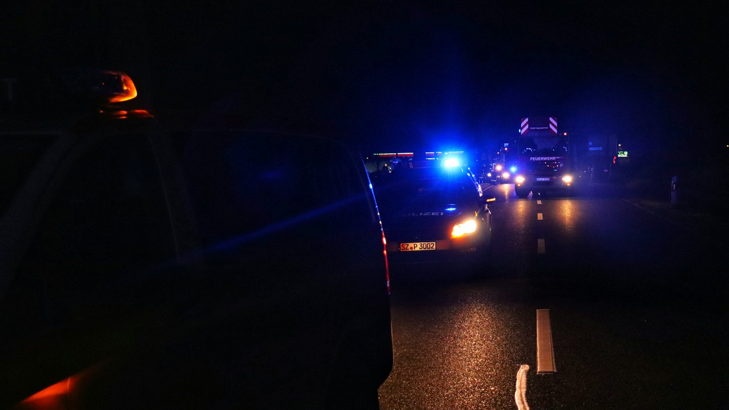 Politieauto en brandweerwagen bij een noodsituatie 's nachts.