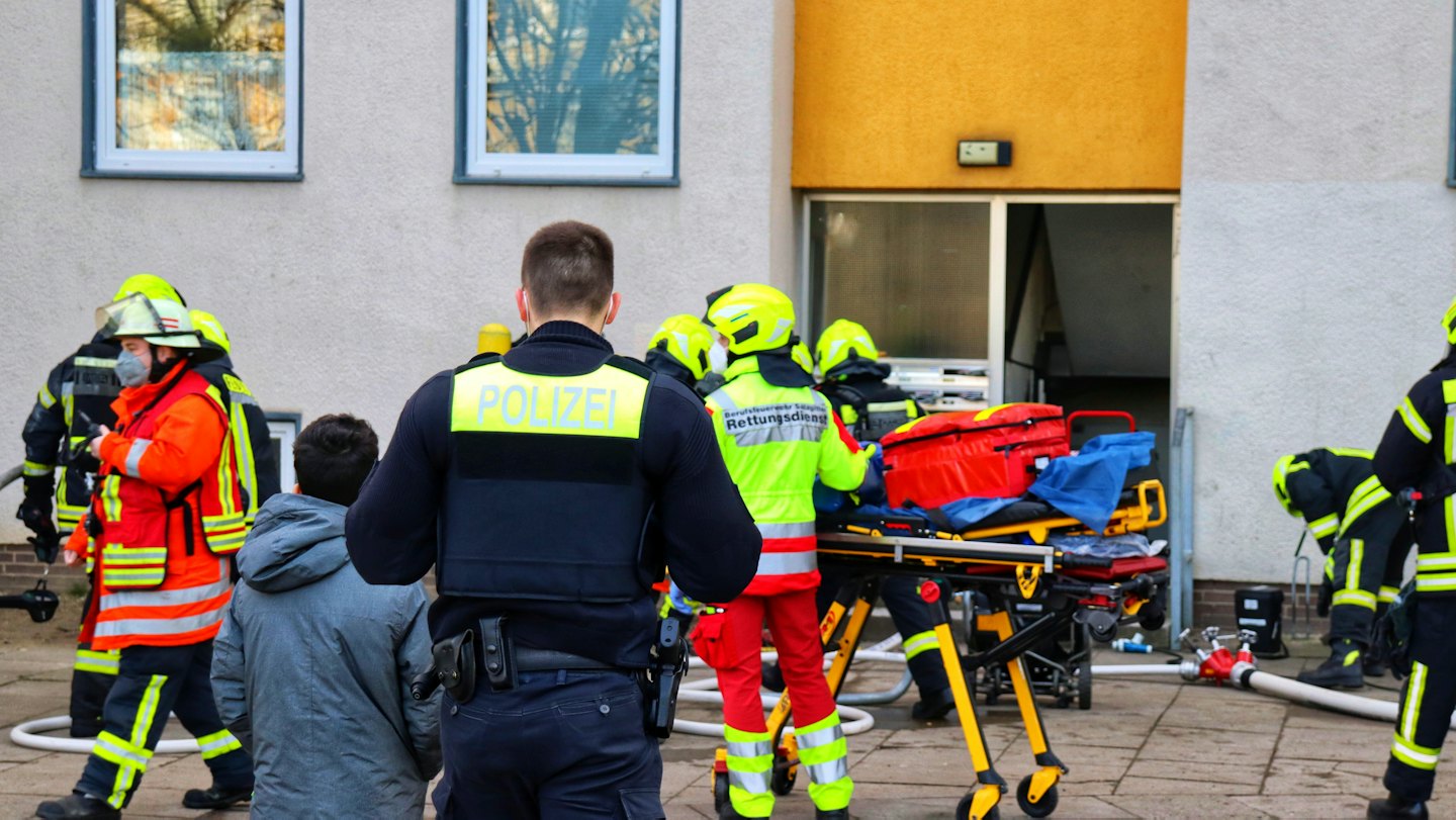 Hulpverleners werken met apparatuur buiten een woongebouw.
