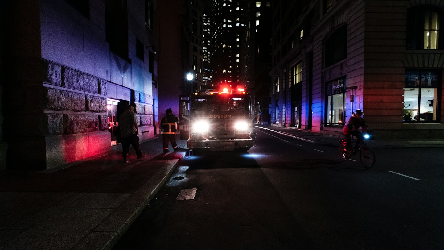 Brandweerauto met zwaailichten op een stadsstraat 's nachts.